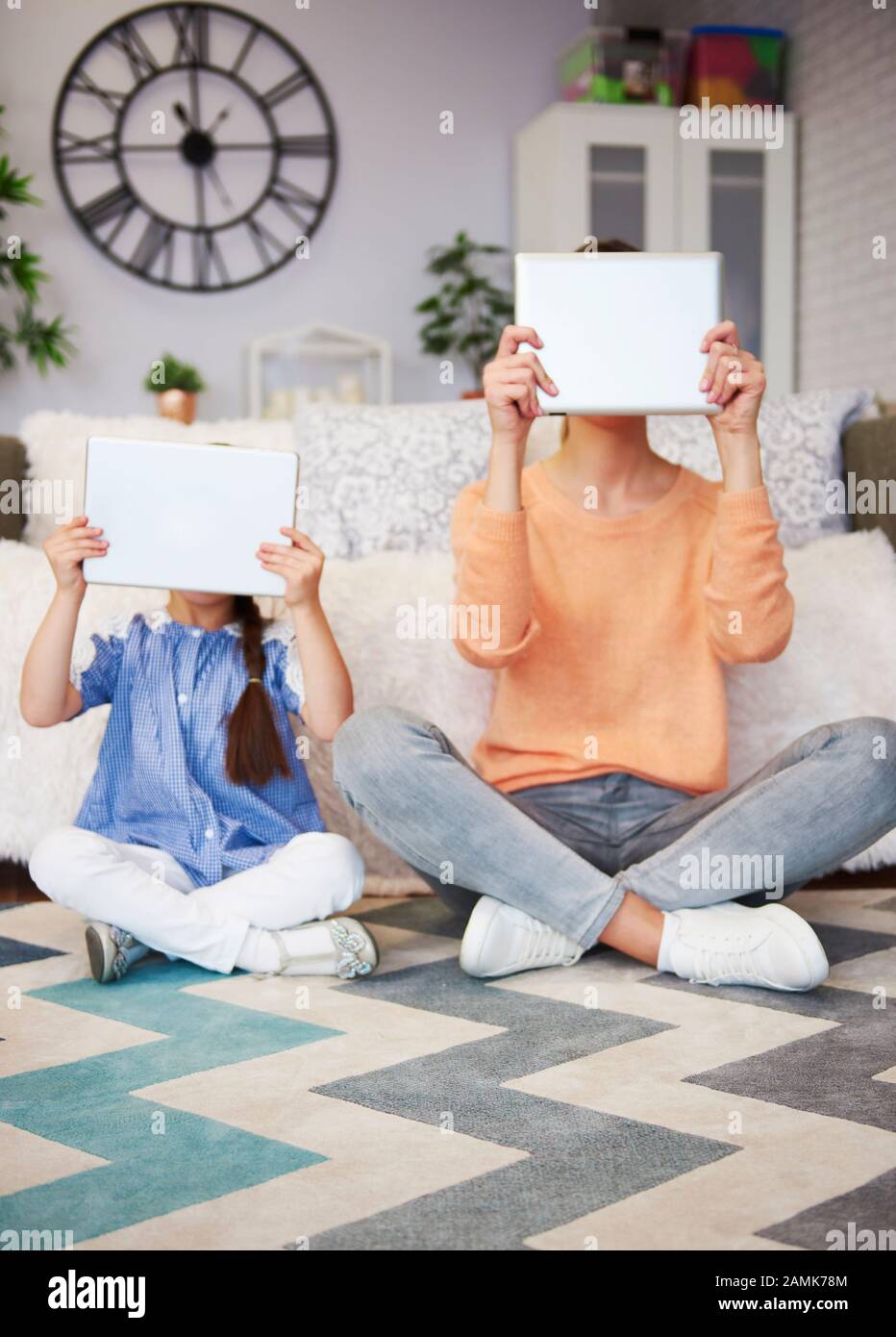 Mutter und Kind, die eine Tablette vor ihrem Gesicht halten Stockfoto