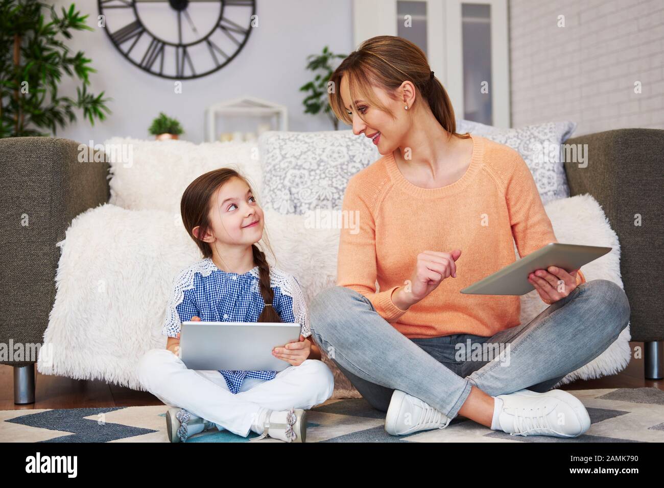 Junge Mutter und ihre Tochter benutzen ein Tablet im Wohnzimmer Stockfoto