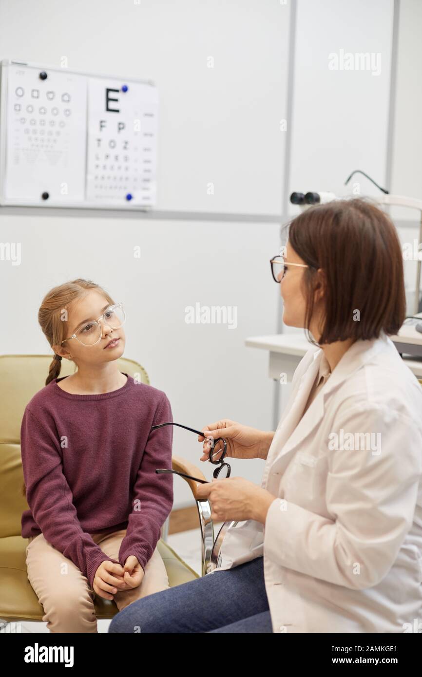 Portrait des süßen Mädchens, das während des Sehtests in der modernen Augenheilkunde auf eine Brille versucht, kopiere Raum Stockfoto