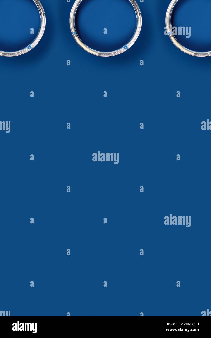 Vertikales Bild. Klassischer blauer Hintergrund mit drei blauen Farbdosen. Flaches Layout, Draufsicht, Kopierbereich. Stockfoto