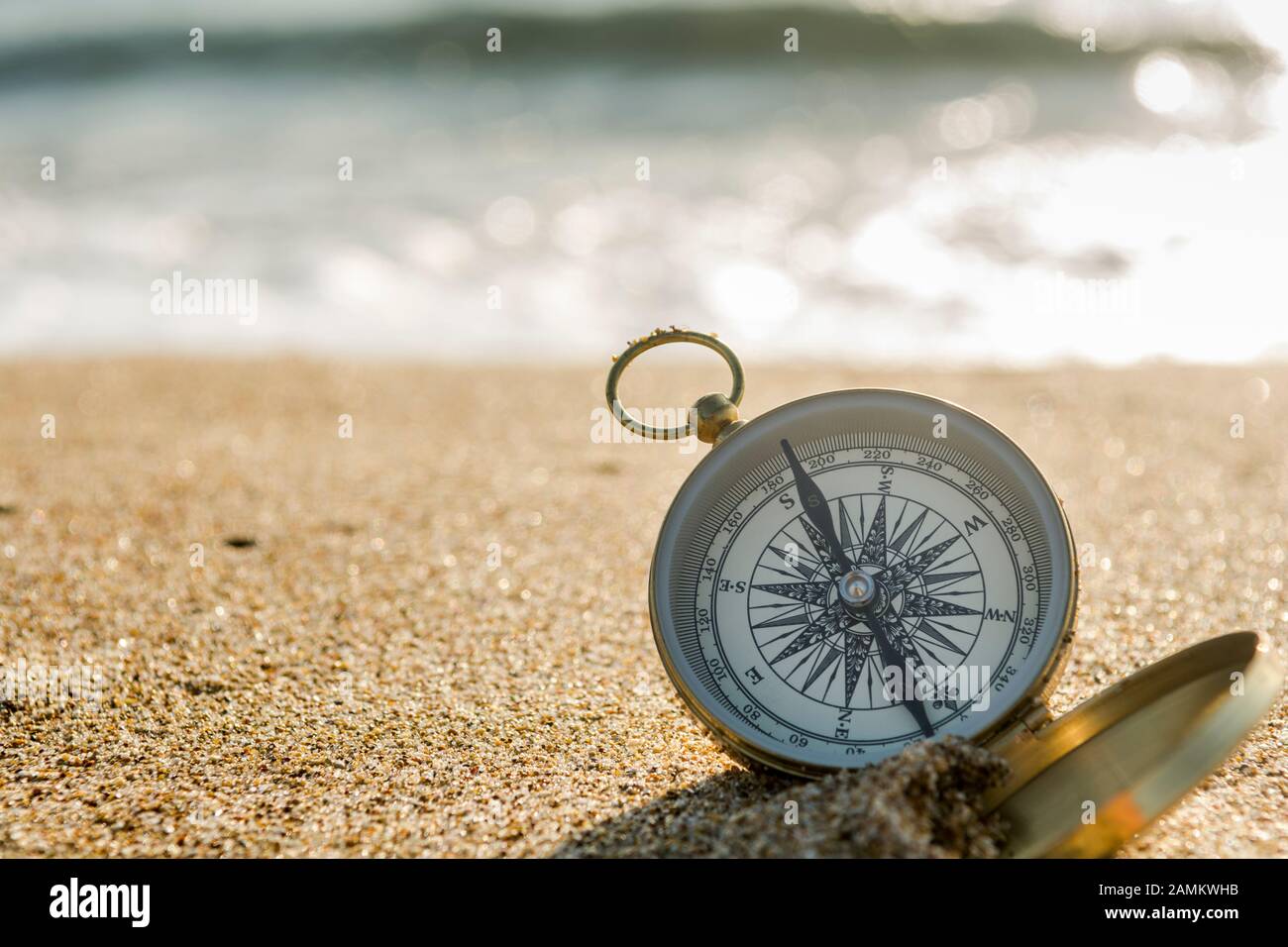 Kompass auf goldenem Sand am Meer Stockfoto