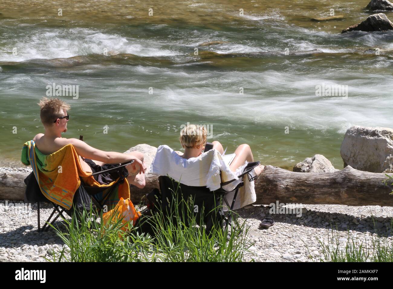 Zwei Männer auf Campingstühlen sonnen sich auf der Isar zwischen Tierparkbrücke und Flaucher. [Automatisierte Übersetzung] Stockfoto