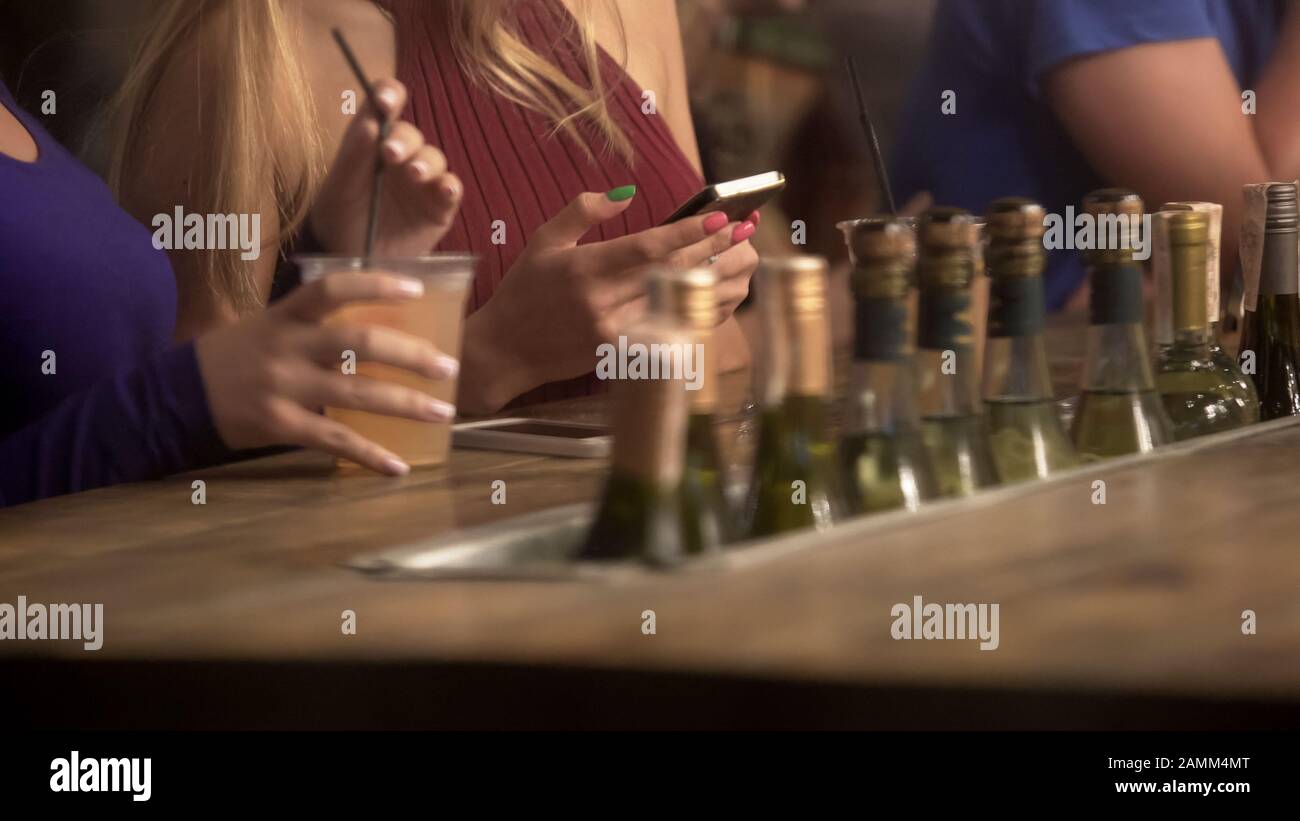 Frauen hängen aus, trinken an der Theke und plaudern online auf Smartphones Stockfoto