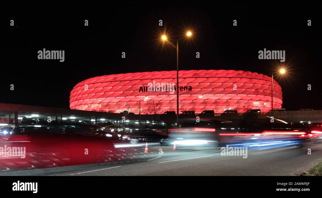 Beleuchteter Parkplatz und Licht aus vorbeifahrenden Autos in der Allianz Arena nach dem Champions-League-Halbfinale FC Bayern München - Real Madrid. Im Hintergrund die rot beleuchtete Allianz Arena. [Automatisierte Übersetzung] Stockfoto