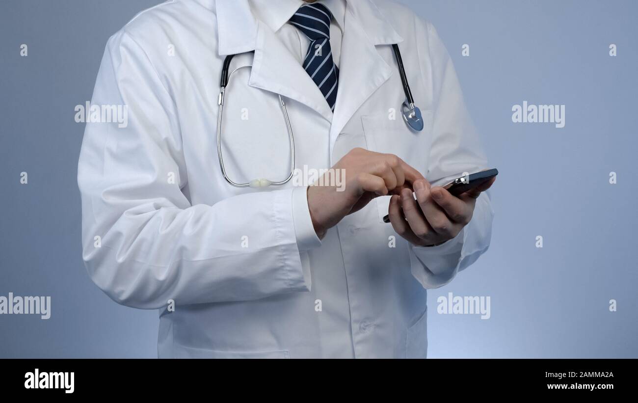 Hausarzt schreibt Nachricht auf einem modernen Smartphone und verwendet intelligente Geräte für die Arbeit Stockfoto
