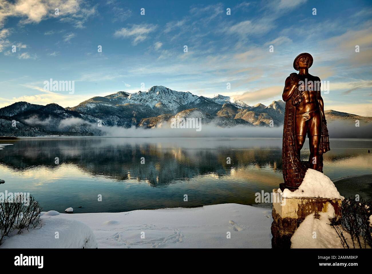 Herzogstand 1.731 m mit Kochelsee, frühmorgens, teils Nebel, Schnee auf dem Gipfel, vor der Skulptur Fischerjung - Fischer vom Kochelsee, die erstmals 1952 aus einer Drahtkonstruktion mit Putz und Ton errichtet wurde, die vom Bildhauer Prof. Richard Miller geschaffen wurde, Renoviert und vor einigen Jahren von Oswald Rifesser aus St. Ulrich in Tyrol, 10.01.2017 [automatisierte Übersetzung] Stockfoto