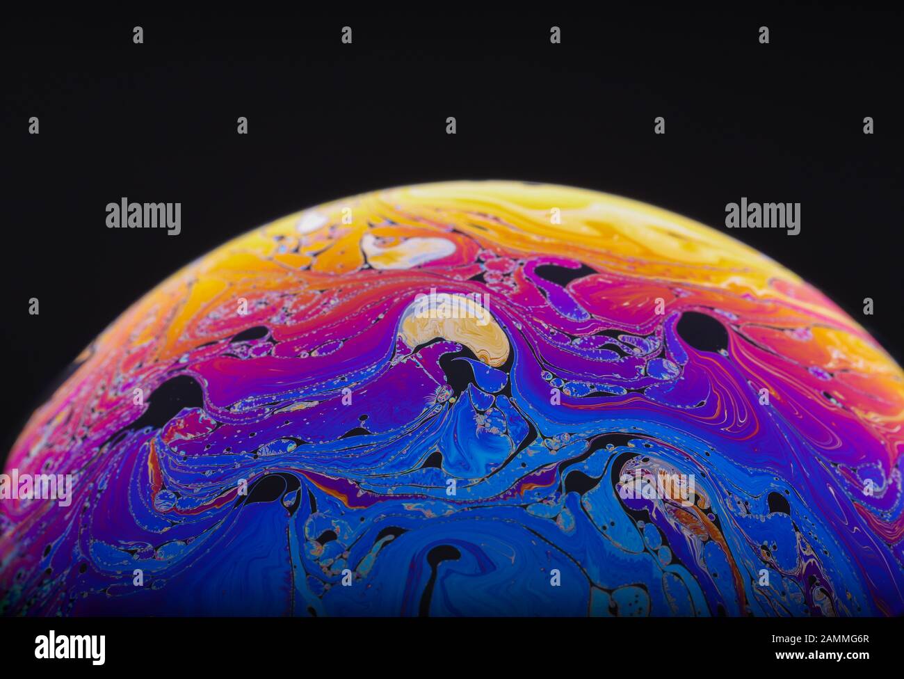 Nahaufnahme des psychedelischen Regenbogens von Farben, die sich in einer Seifenblase mischen und wirbeln, um wie eine Fantasy-Galaxie oder ein Planet zu aussehen, der einen schwarzen Hintergrund isolierte Stockfoto