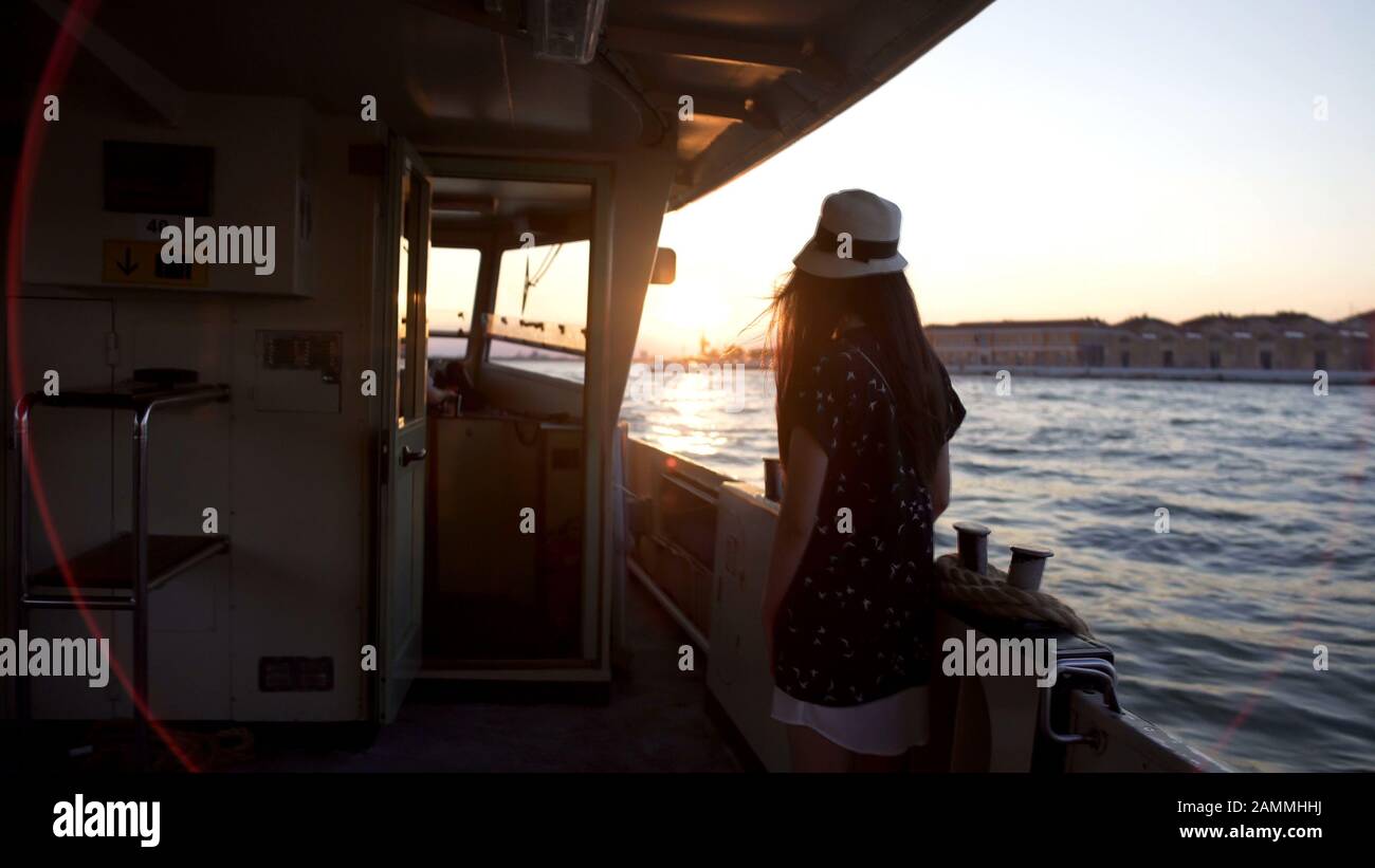 Einsame Touristin steht an Bord des Schiffes und betrachtet Venedig aus dem Wasser Stockfoto