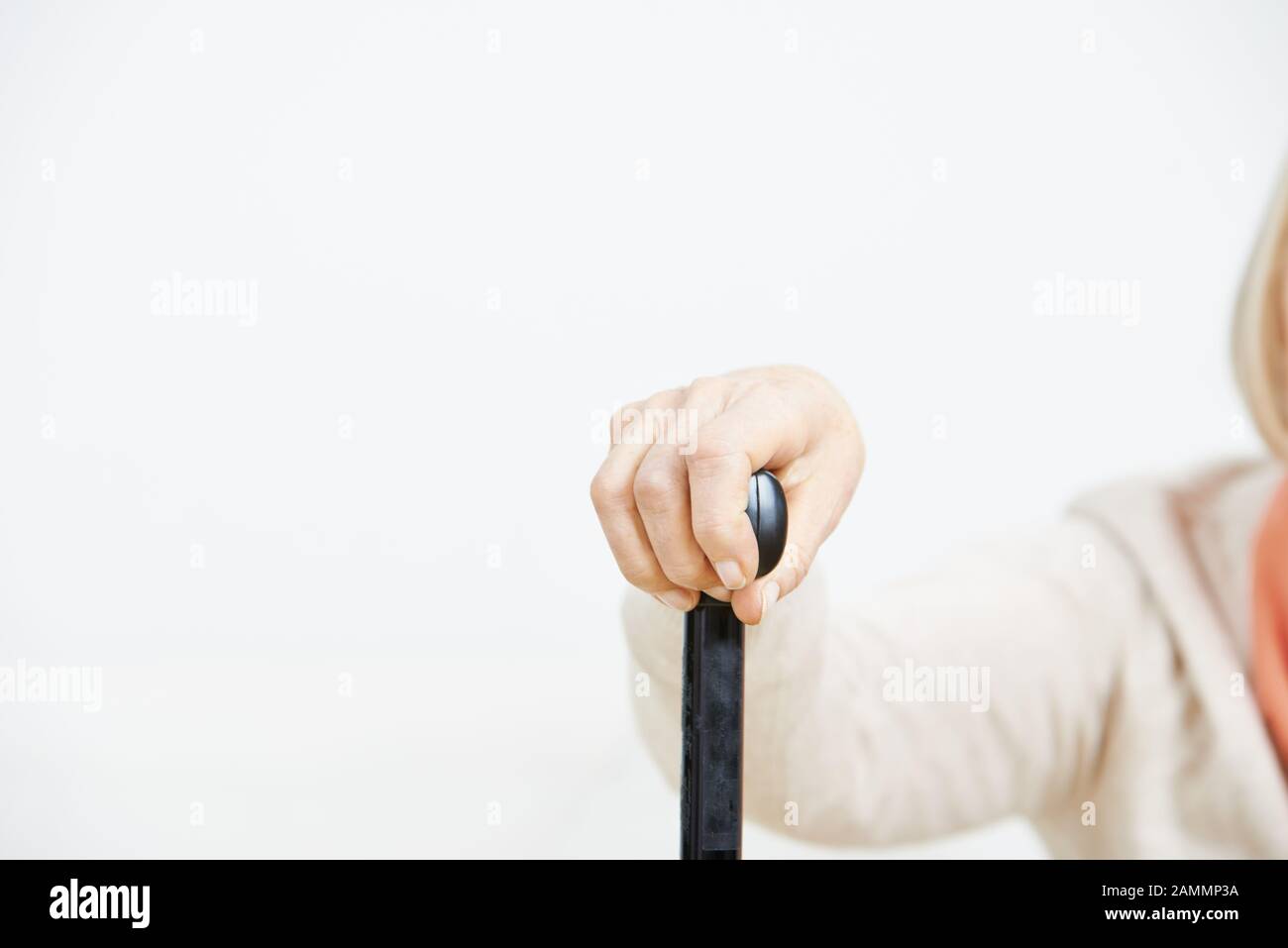 Die alte Frau hält ihre Hand auf einem Krückenstock Stockfoto