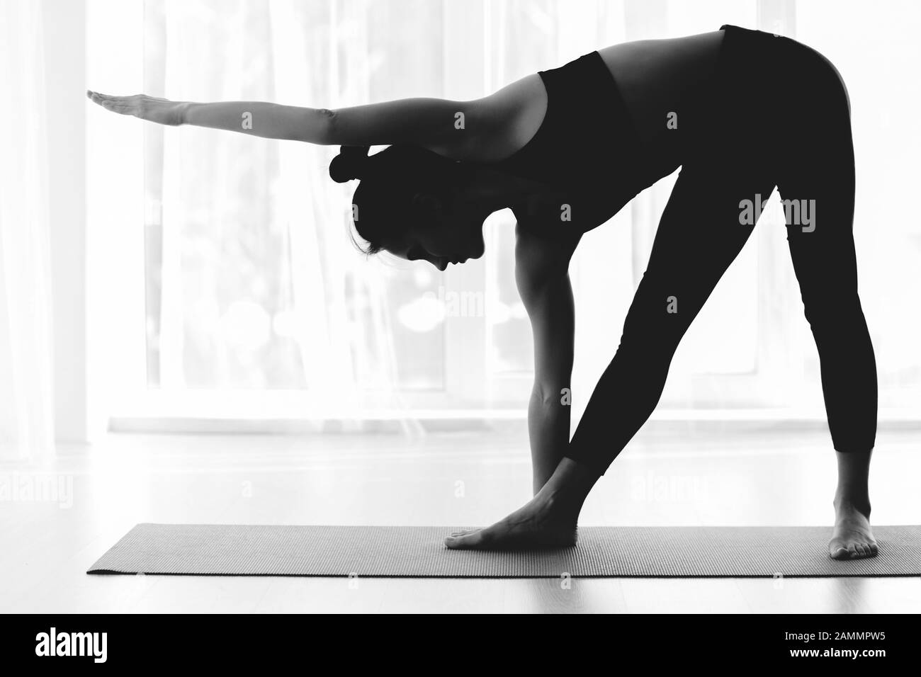 Sportliche Frau, die Yoga praktiziert und Dreieck Asana macht Stockfoto