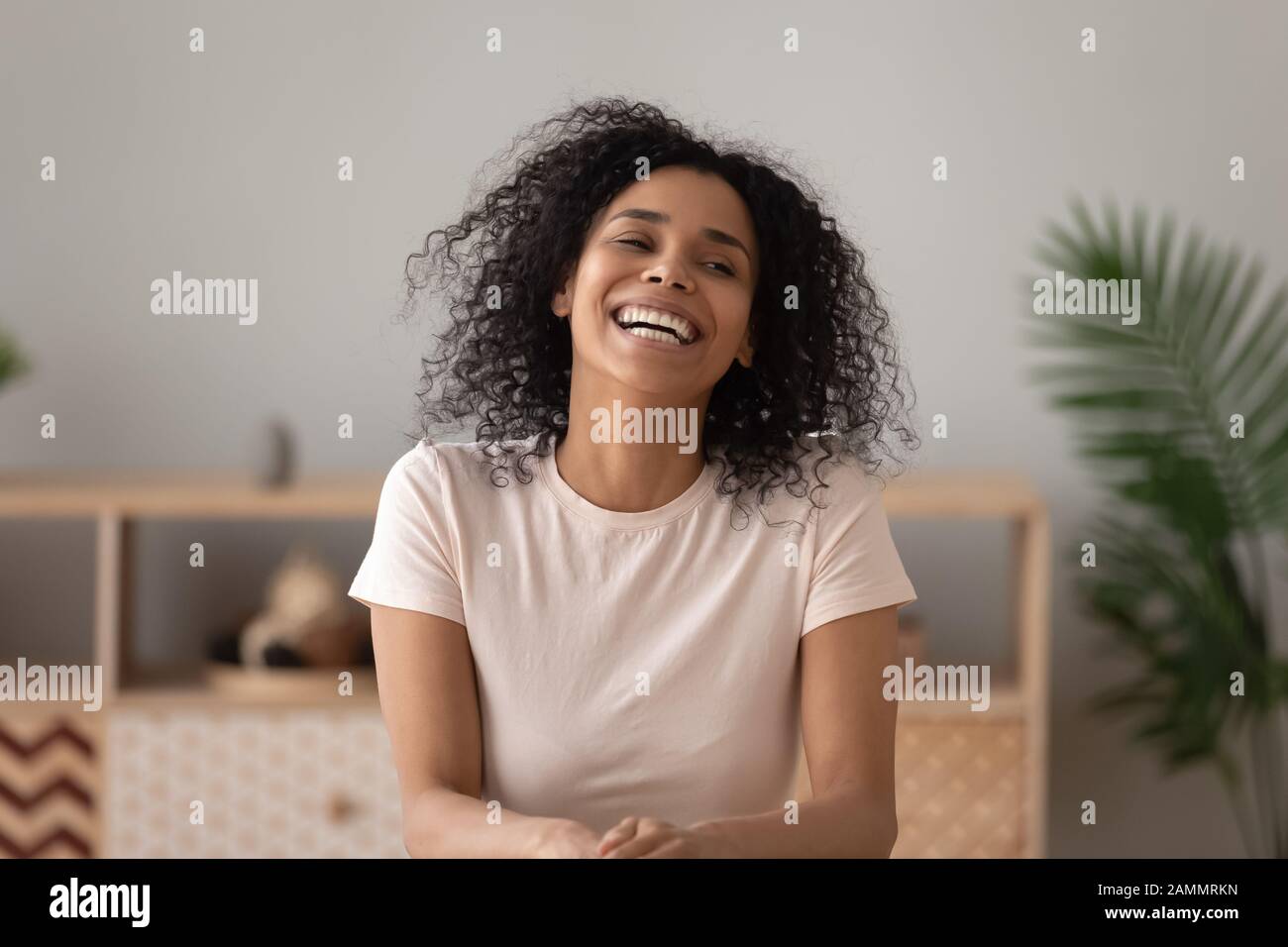 Glückliche Frau, die in geschlossenen Räumen sitzt, fühlt sich überglücklich an Stockfoto