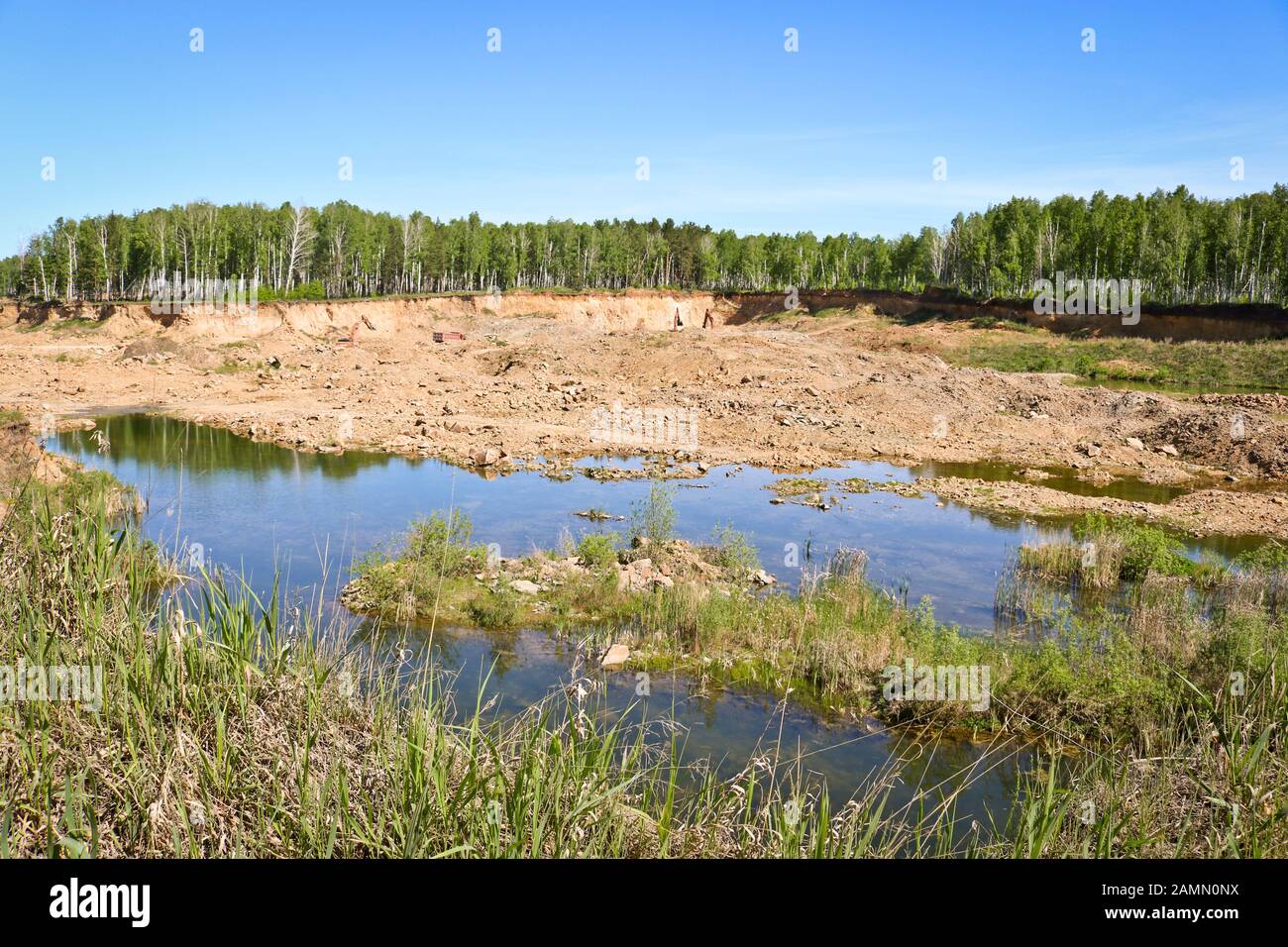 Entwicklung von Sandbruch. Bagger und Bergbaugeräte in der Ferne. Überschwemmte verbrachten einen Teil des Steinbruchs. Gewinnung von Sand und Baumaterial Stockfoto