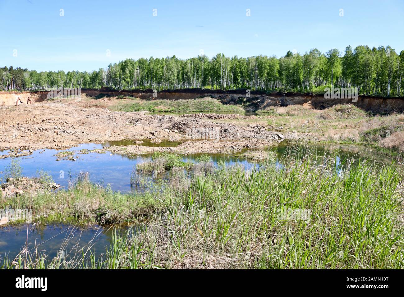 Entwicklung von Sandbruch. Bagger und Bergbaugeräte in der Ferne. Überschwemmte verbrachten einen Teil des Steinbruchs. Gewinnung von Sand und Baumaterial Stockfoto