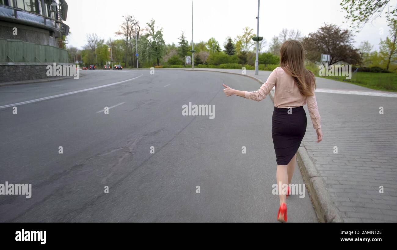 Junge, schöne Geschäftsfrau, die auf der Straße spazieren geht und versucht, ein Auto anzukuppieren Stockfoto