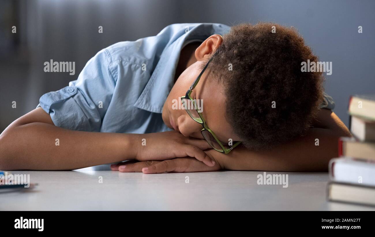 Müde Schüler schlafen, sitzen am Schreibtisch, harter Bildungsprozess, überarbeiteter Junge Stockfoto