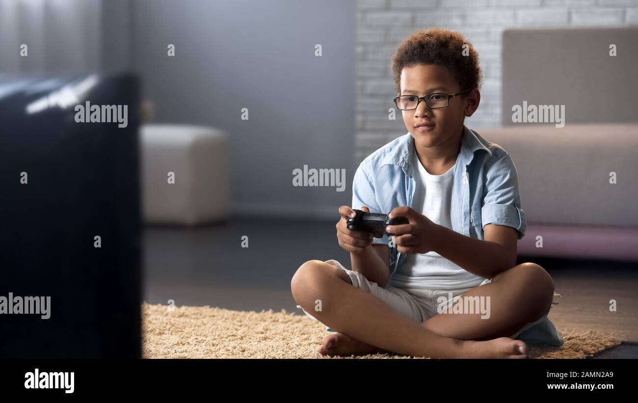 Afro-amerikanischer Schuljunge verbringt seine Freizeit damit, Spiele auf Konsole und Freizeit zu spielen Stockfoto