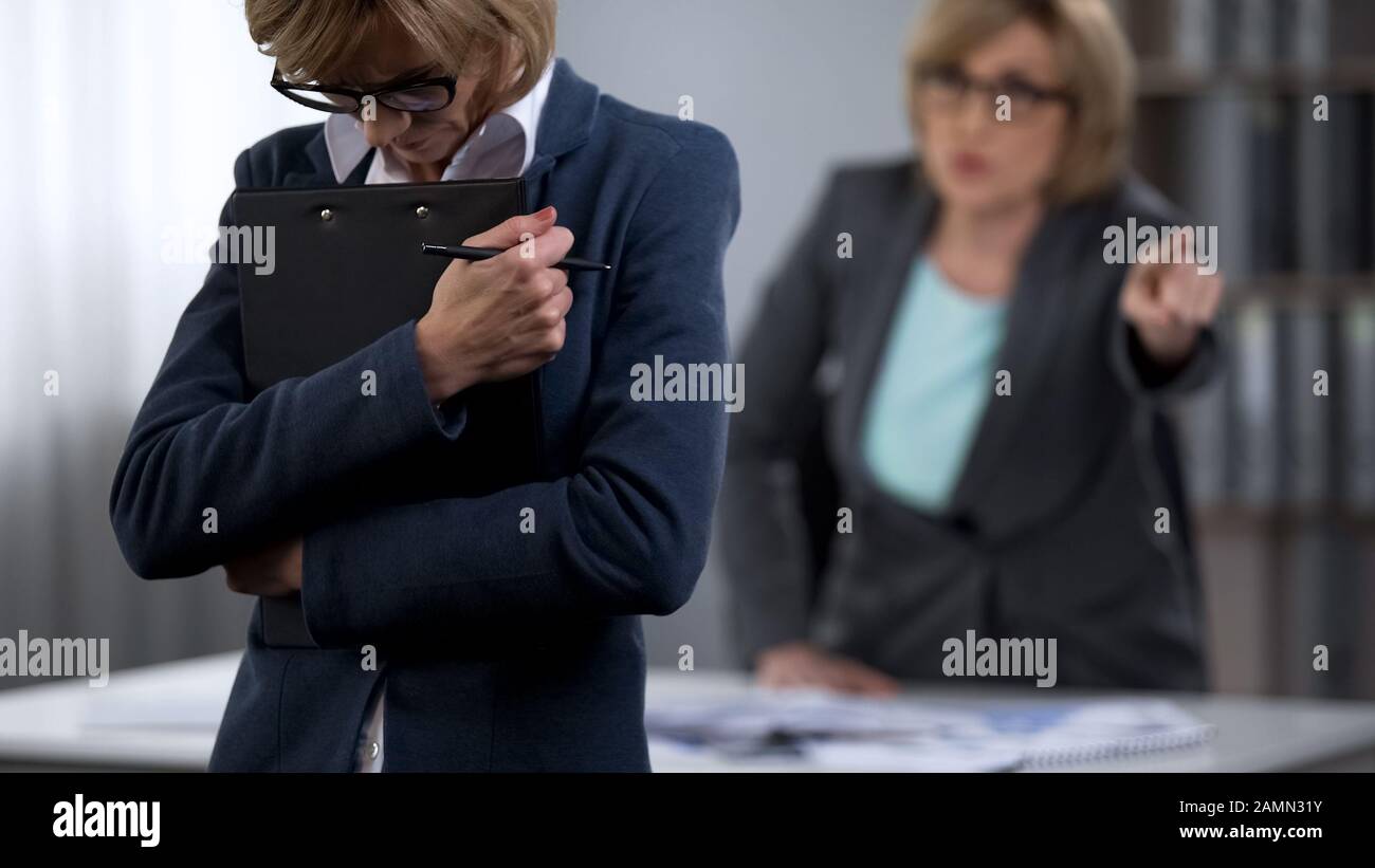 Lady Boss tritt traurige weibliche Angestellte aus dem Büro, Kündigung des Arbeitsverhältnisses Stockfoto