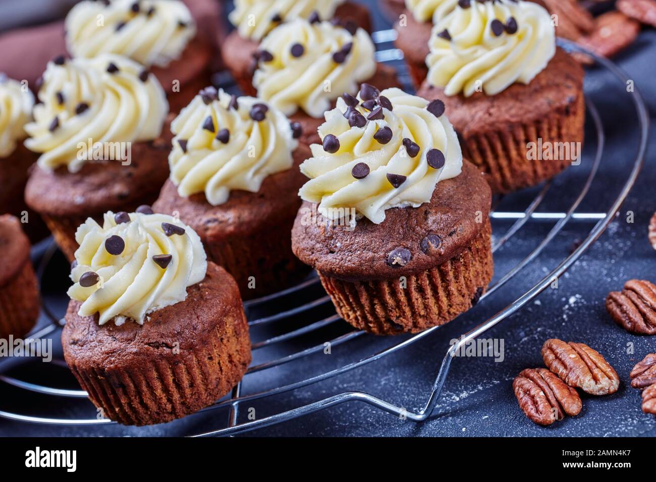 Nahaufnahme von Schokoladenkuchen mit Vanille-Buttercreme-Verwirbelung auf einem Metallkuchengestell auf einem Betontisch, horizontale Ansicht von oben Stockfoto