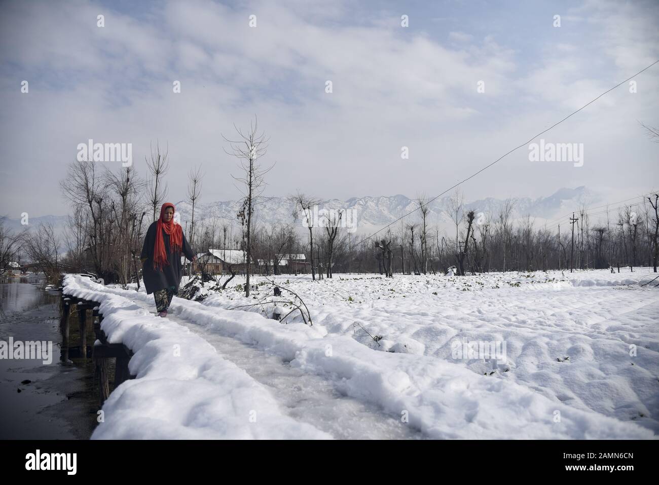 Eine Kaschmiri-Frau läuft nach dem frischen Schneefall in Srinagar auf schneebedeckte Holzbrücke.Aufgrund der starken Schneefälle in den letzten 48 Stunden gab es mehrere Lawinen, in denen mindestens 4 indische Armeesoldaten und 5 Zivilisten Im indianischen Kaschmir ermordet wurden. Stockfoto