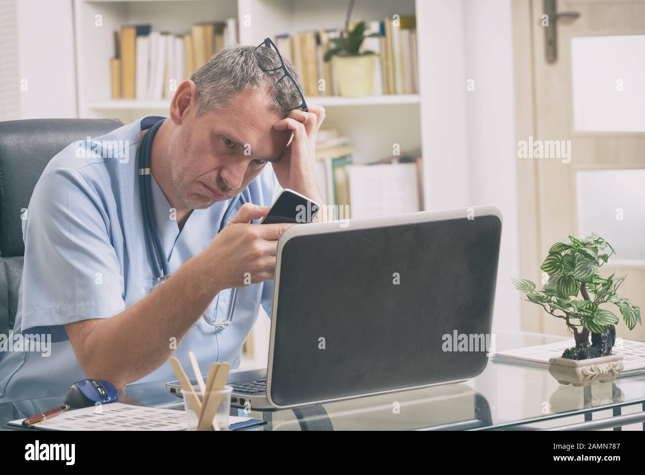 Überarbeitete Arzt sitzt in seinem Büro Stockfoto