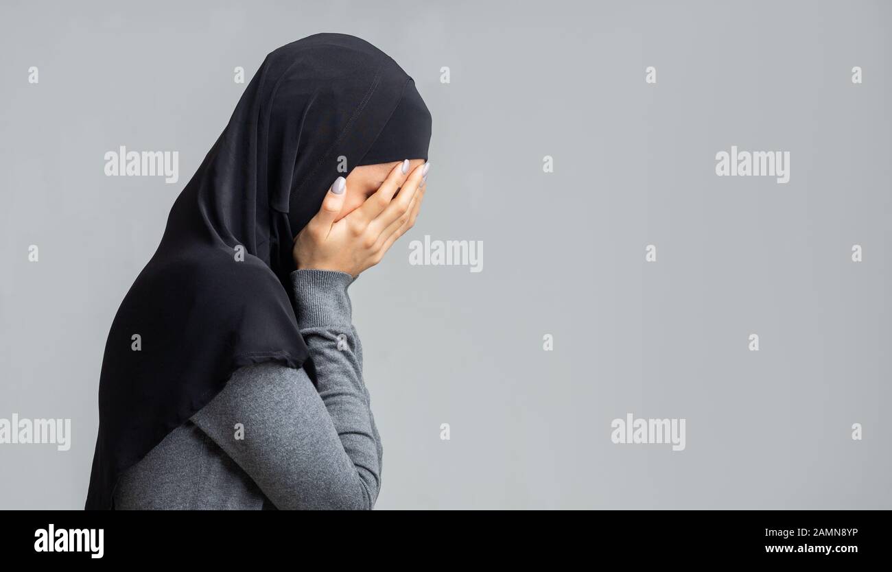 Profilporträt der weinenden muslimischen Frau, die ihr Gesicht mit den Händen bedeckt Stockfoto
