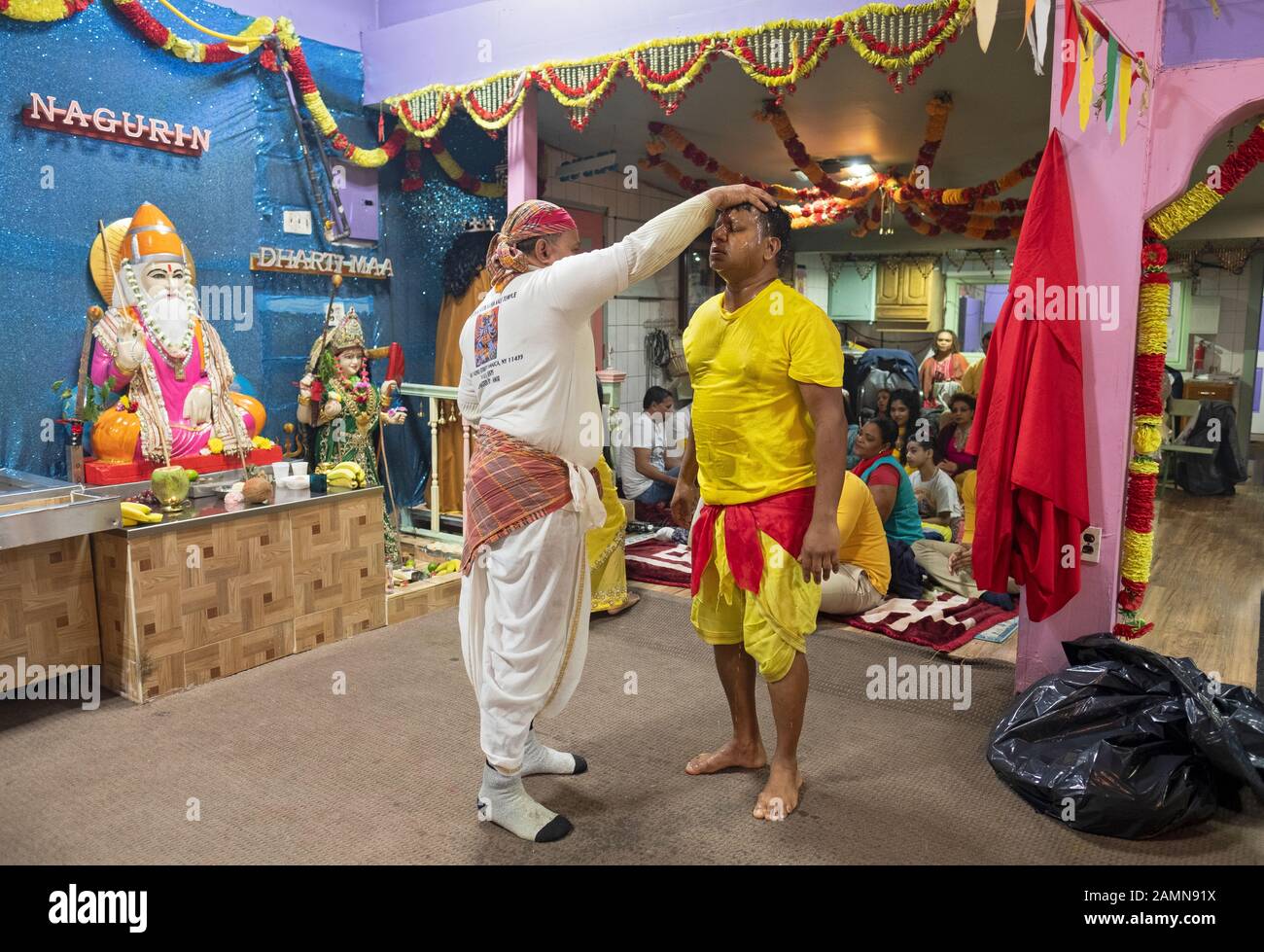 Ein Hindu-Priester berührt einen seiner Anbeter während des Sonntagsgottesdienstes in Jamaika, Queens, New York City. Stockfoto
