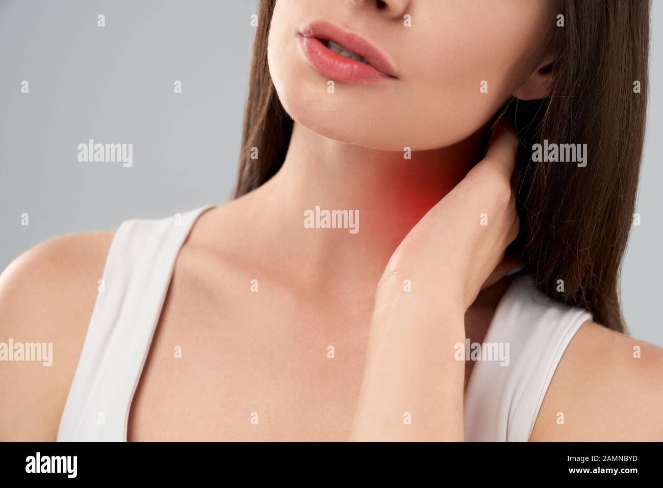 Clolse von Incognito kaukasische Frau in weißem Hemd Posing über Grau isoliert Hintergrund und Hals berühren mit der Hand wegen der Schmerzen. Crop von brunette Atmen mit den Mund. Stockfoto