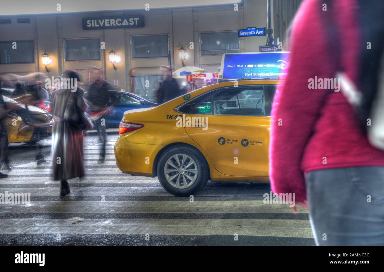 Lange Belichtung einer Straße in Manhattan nachts während der Weihnachtszeit. Schnelle Bewegung von Menschen, die eine Straße überqueren. Selektive Fokussierung auf gelbe Taxi-Taxis. Stockfoto