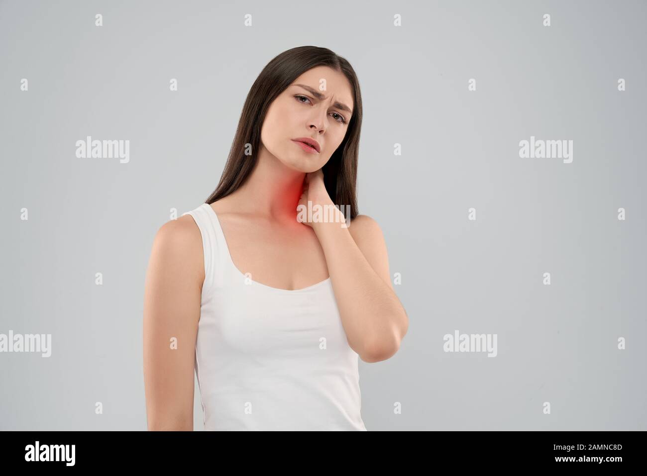 Junge kaukasier Frau in Weiß shirt über Grau isoliert Hintergrund Hals berühren mit der Hand mit schmerzhaften Ausdruck wegen der Schmerzen. Vorderansicht des Brünette mit offenen Mund an Kamera schaut. Stockfoto