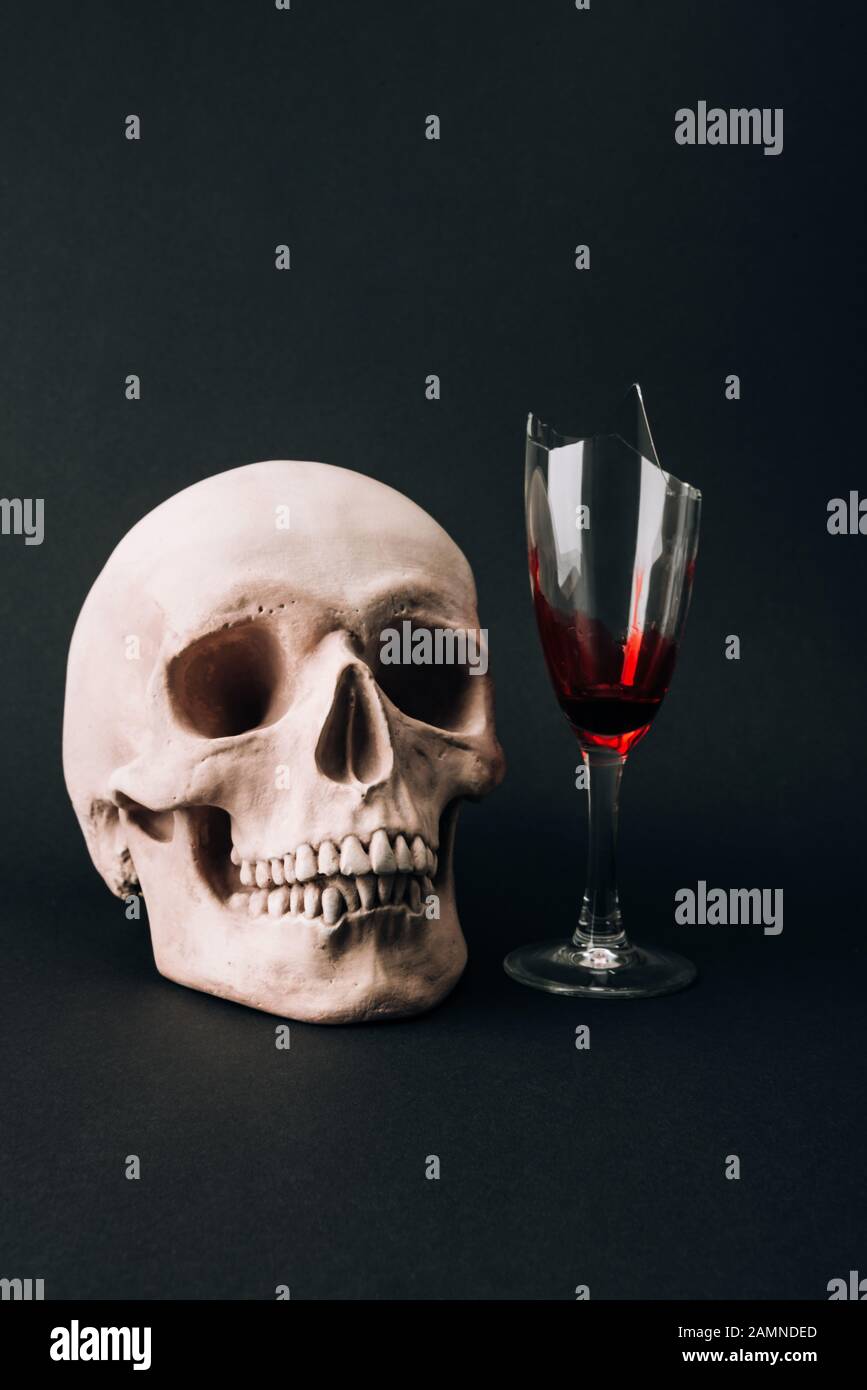 Schädel und zerbrochenes Glas mit Blut isoliert auf Schwarz Stockfoto