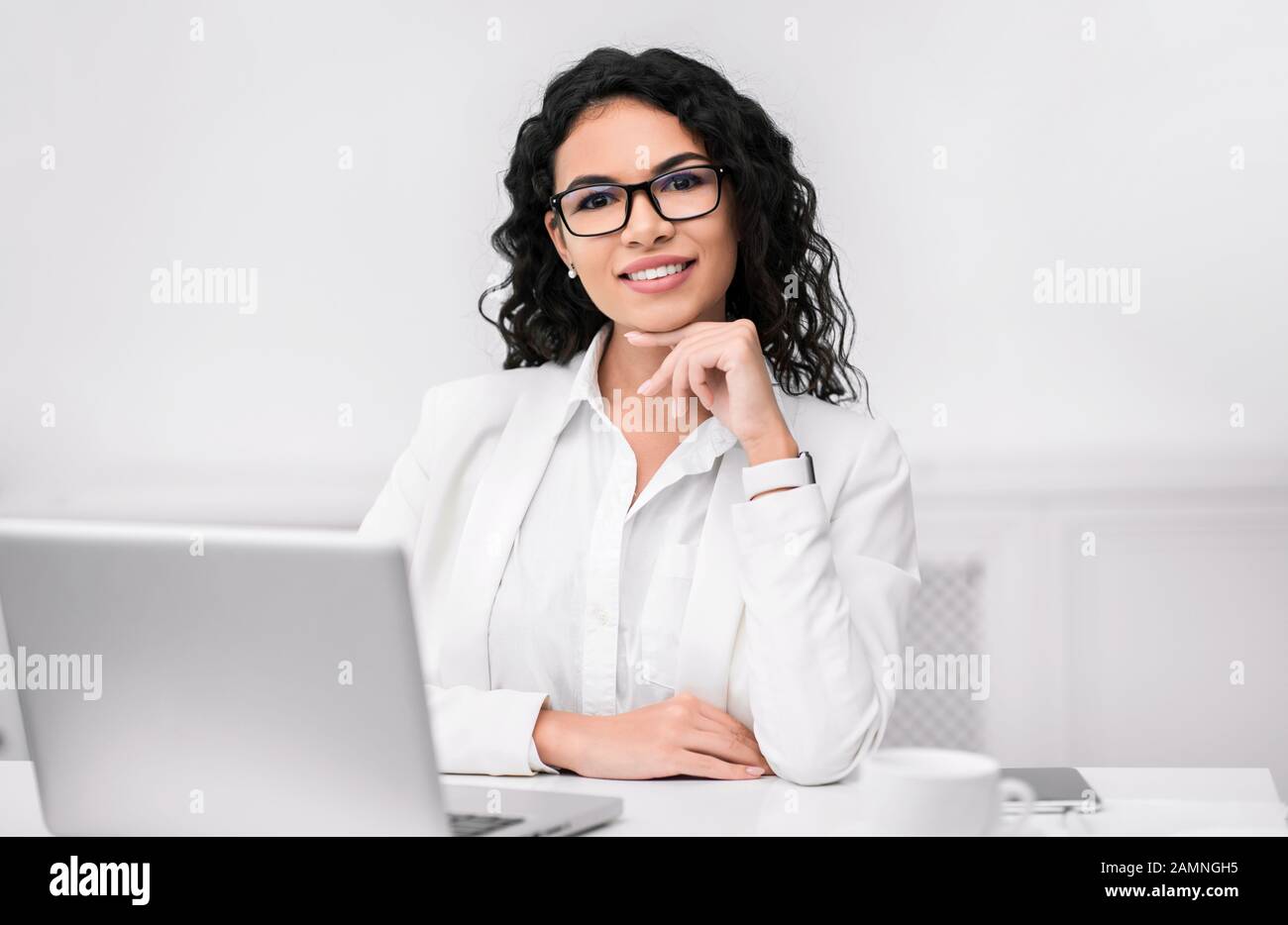 Hispanischer Manager lächelt mit der Hand am Kinn an der Kamera Stockfoto