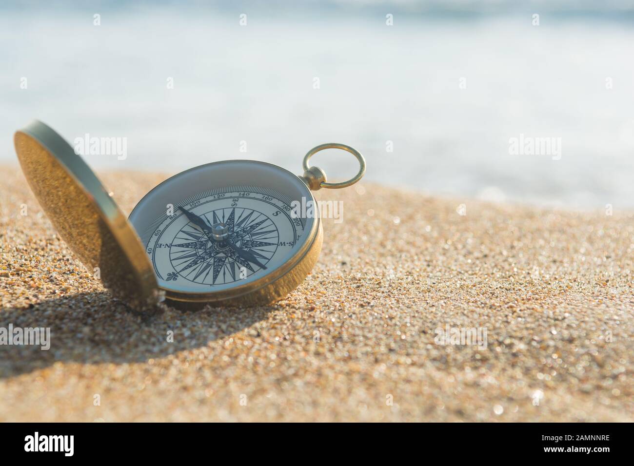Kompass auf goldenem Sand am Meer Stockfoto