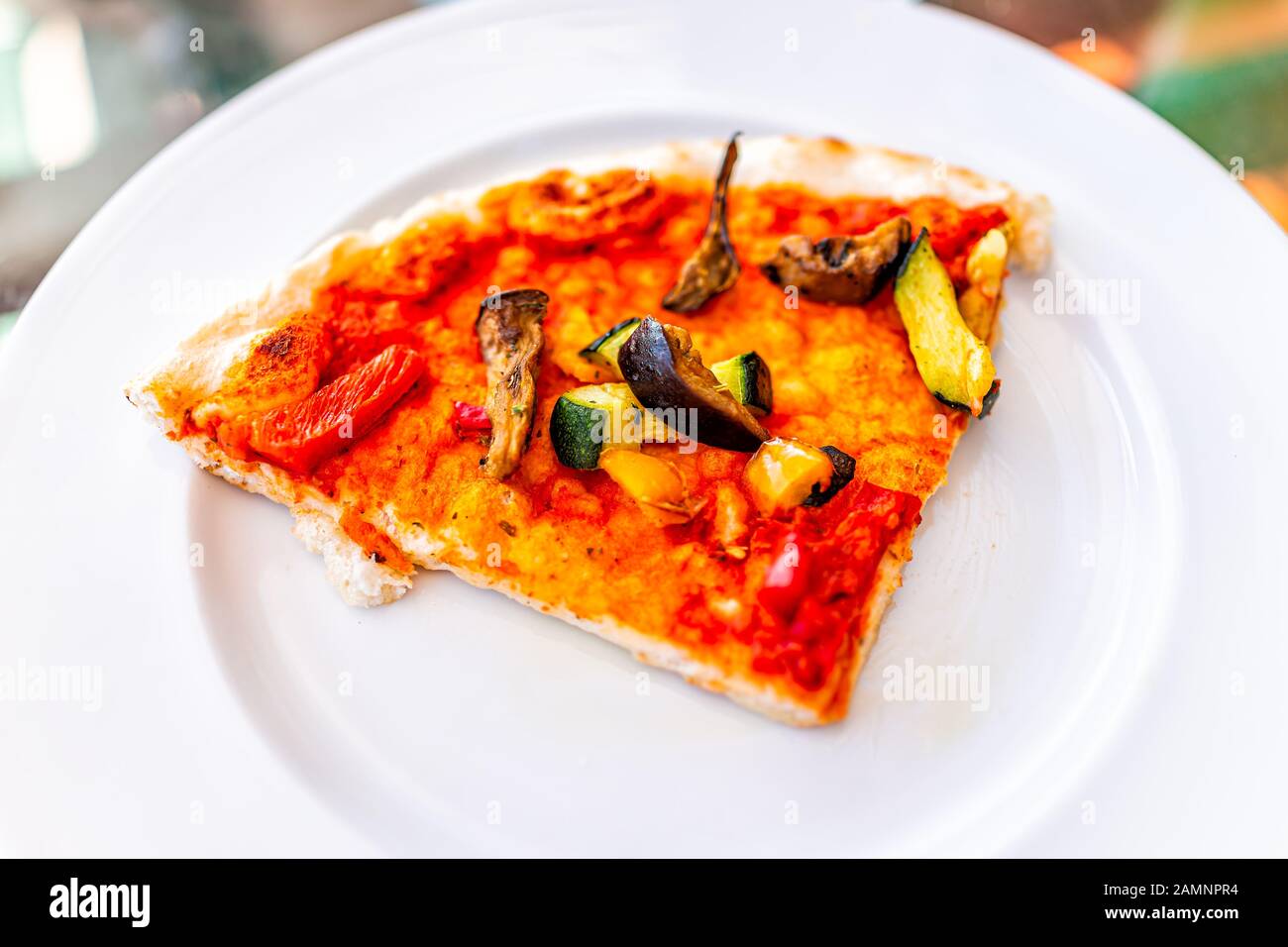 Nahaufnahme über der Makroansicht der Pizzascheibe auf weißem Teller in Italien mit veganer Tomatensauce gehackte Zucchini-Gemüse und Pilze Stockfoto