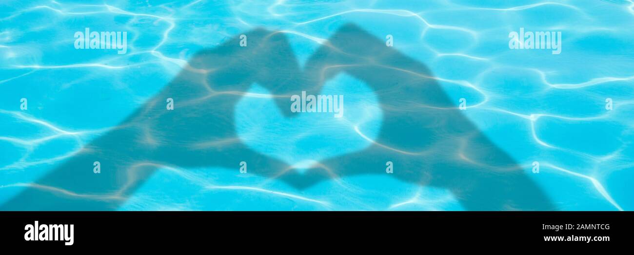 Schatten der Hände bilden ein Herz auf blauem Schwimmbadwasserhintergrund, Panorama-Valentinstag oder Sommerbanner Stockfoto