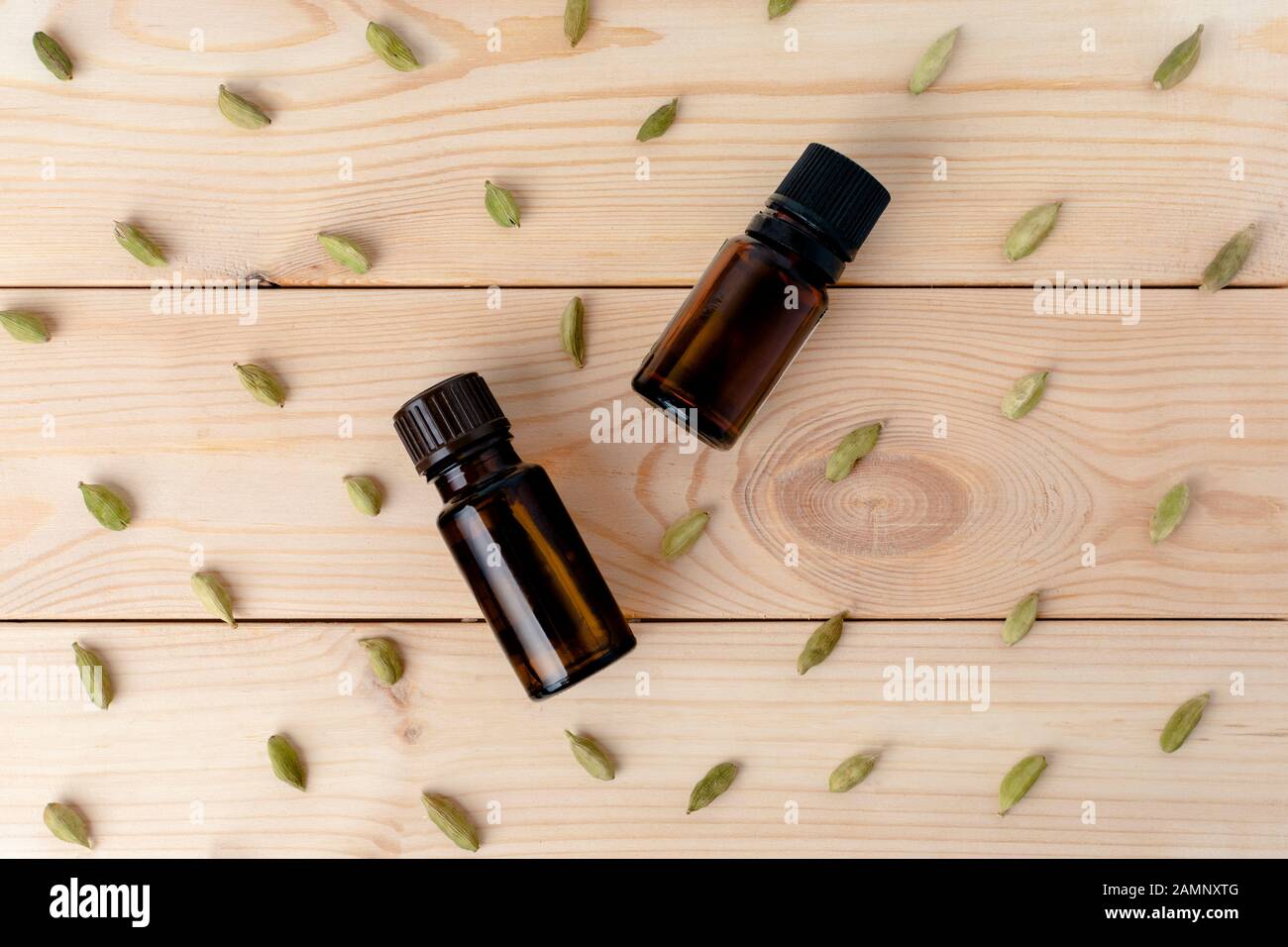 Zwei Glasflaschen mit Kardamom auf hellem Holzhintergrund. Flaches Lay. Stockfoto