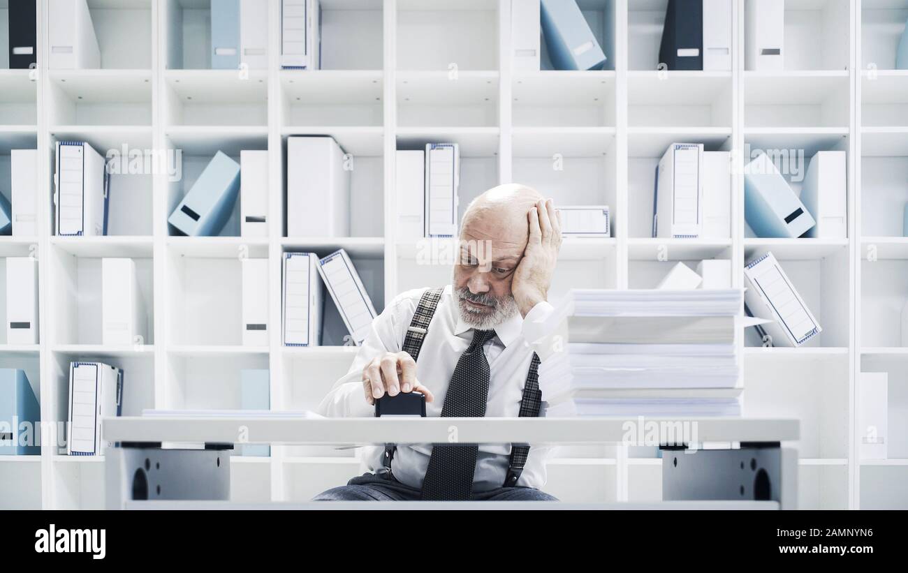 Leitender Angestellter der Unternehmensleitung, der im Büro eine langweilige Arbeit macht, stempelt er Papierkram Stockfoto