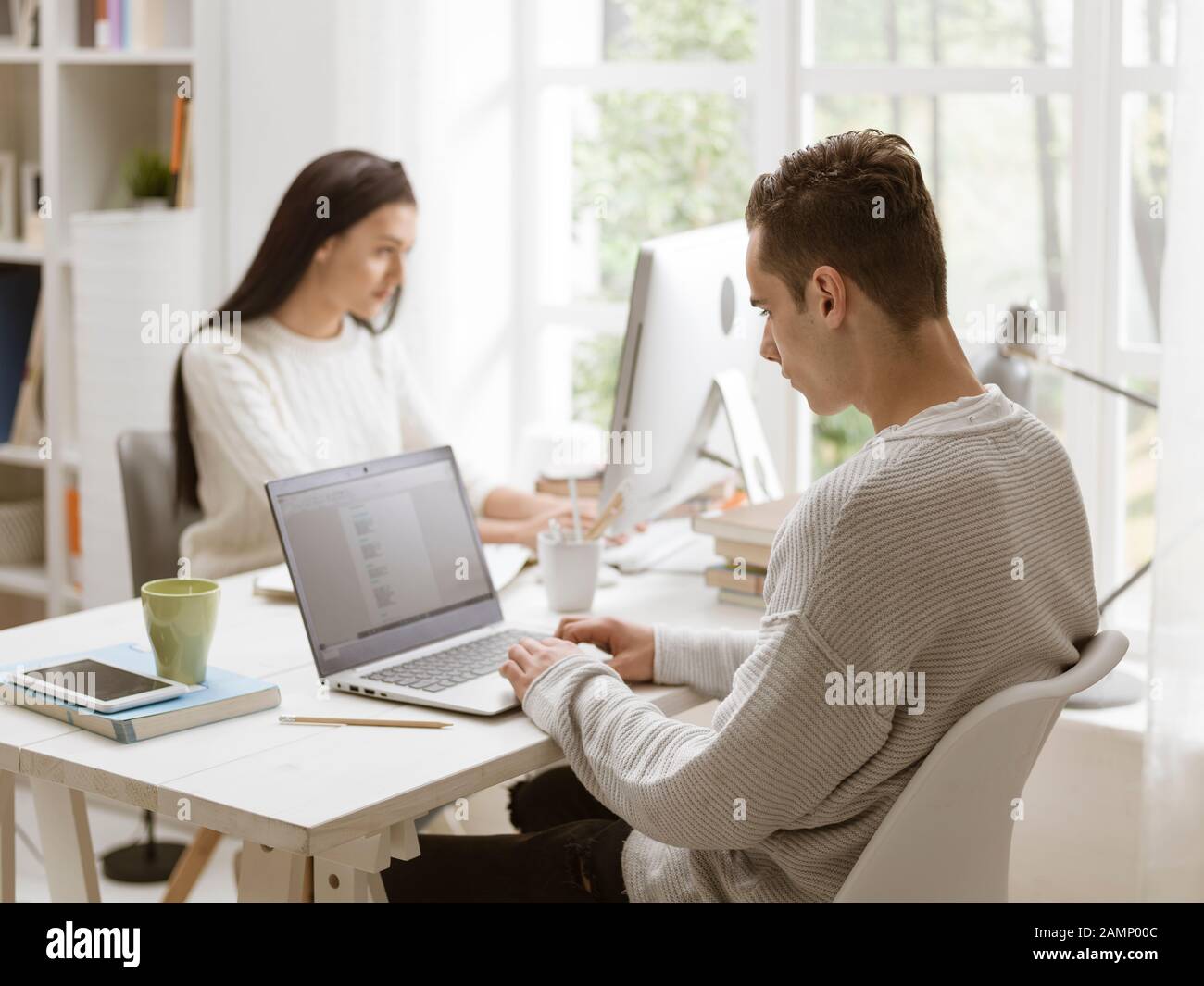 Studenten, die am Schreibtisch in der Bibliothek sitzen, studieren und verbinden sich online Stockfoto