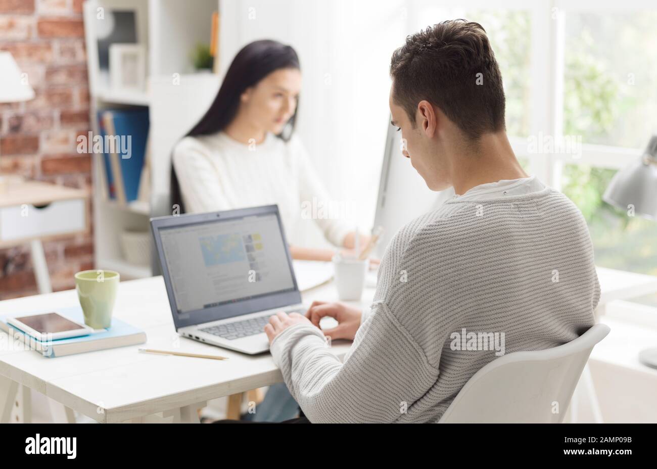 Studenten, die am Schreibtisch in der Bibliothek sitzen, studieren und verbinden sich online Stockfoto