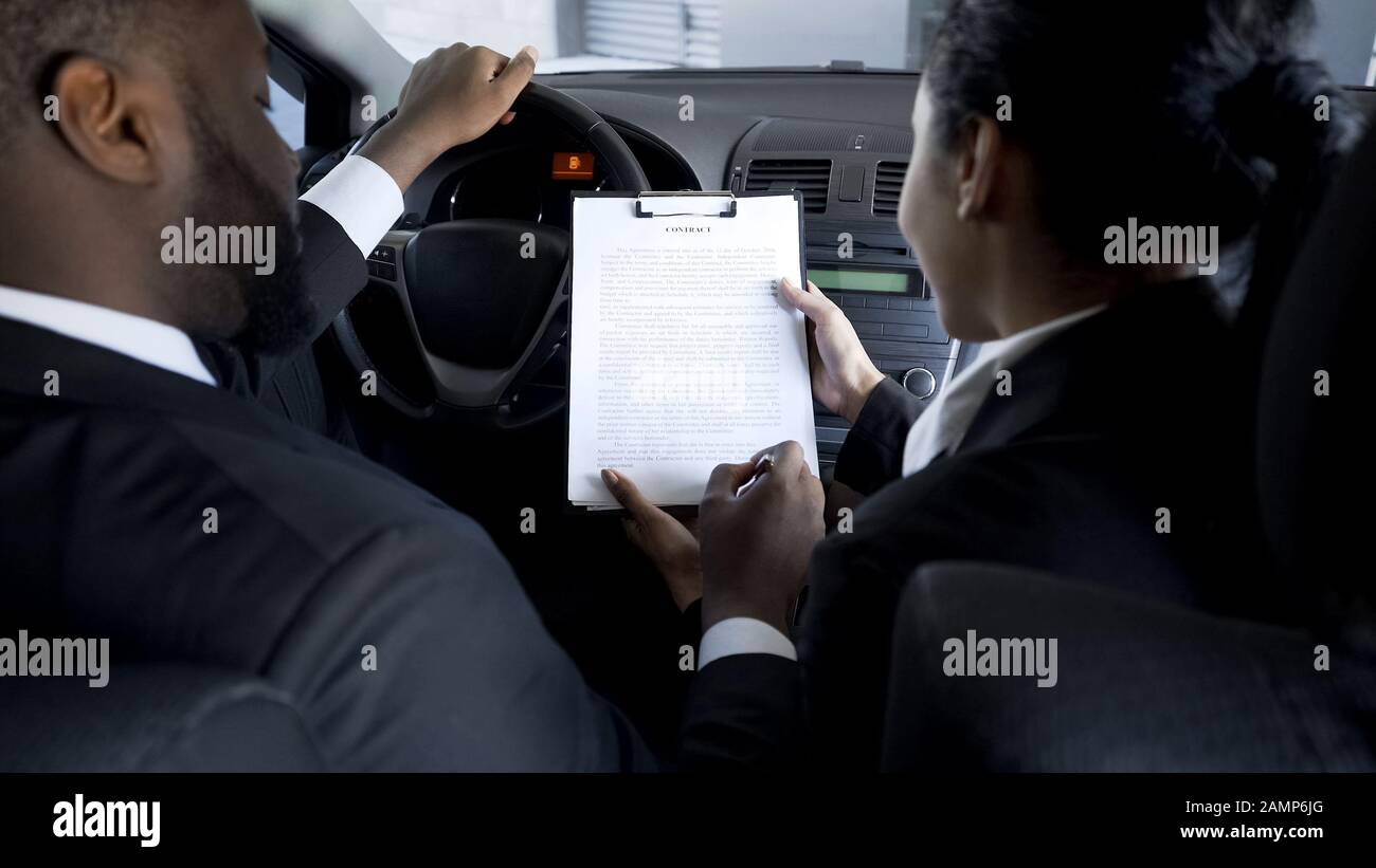 Unternehmer unterzeichnen riskanten Vertrag mit weiblicher Partnerin im Auto, Schattengeschäft Stockfoto