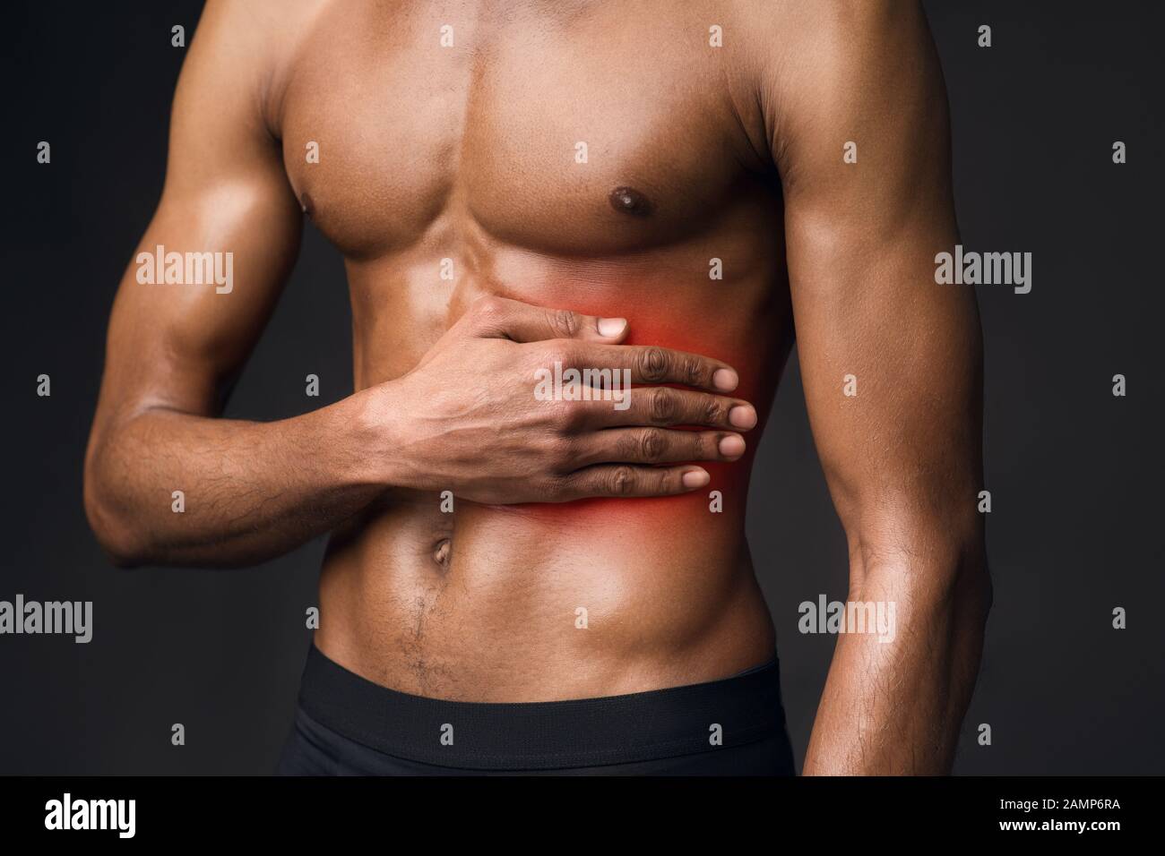 Unerkennbarer afro-Kerl, der unter Schmerzen auf der linken Seite leidet Stockfoto