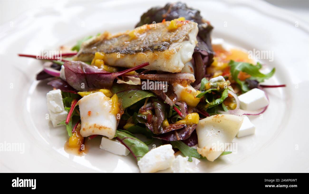 Ein Restaurant Hauptgericht Schüssel, Seebarsch und Calamari mit gemischten Salat und Feta. Stockfoto