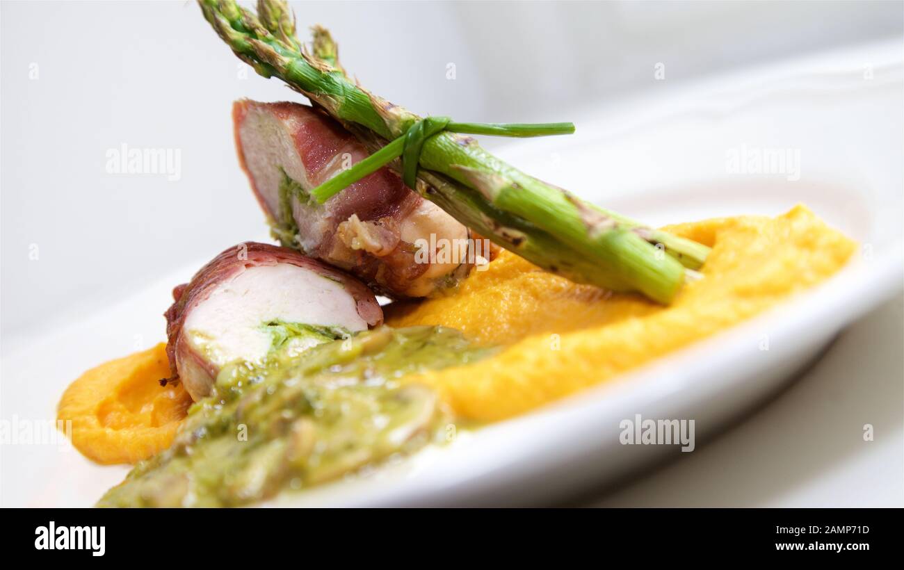 Ein Restaurant Hauptgericht Reisgericht mit Hähnchen in Parmaschinken eingewickelt serviert mit Spargel, Pilze und Süßkartoffel-Püree. Stockfoto