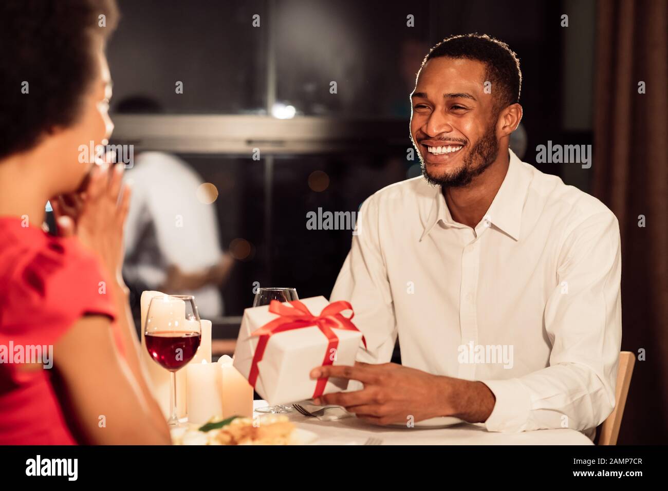 Afroamerikanischer Mann Schenkt Überraschte Frau Im Restaurant Ein Geschenk Stockfoto