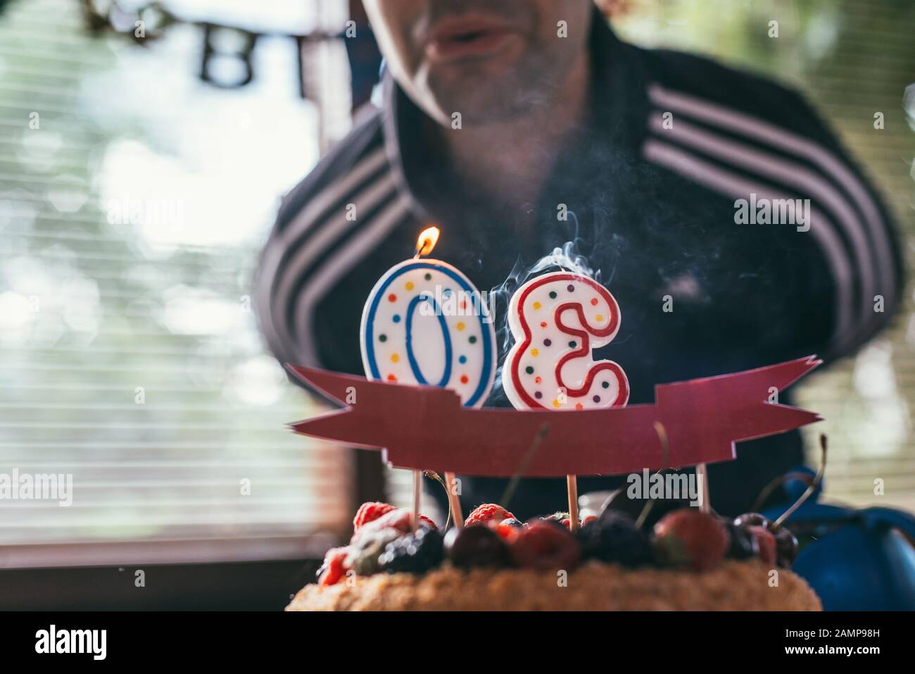 Geburtstagskind bläst die Kerzen in Form von 30 auf Himbeeren blackberry Geburtstagskuchen aus. Selektives Fokusmakro mit flachem Freiheitsgrad. Stockfoto