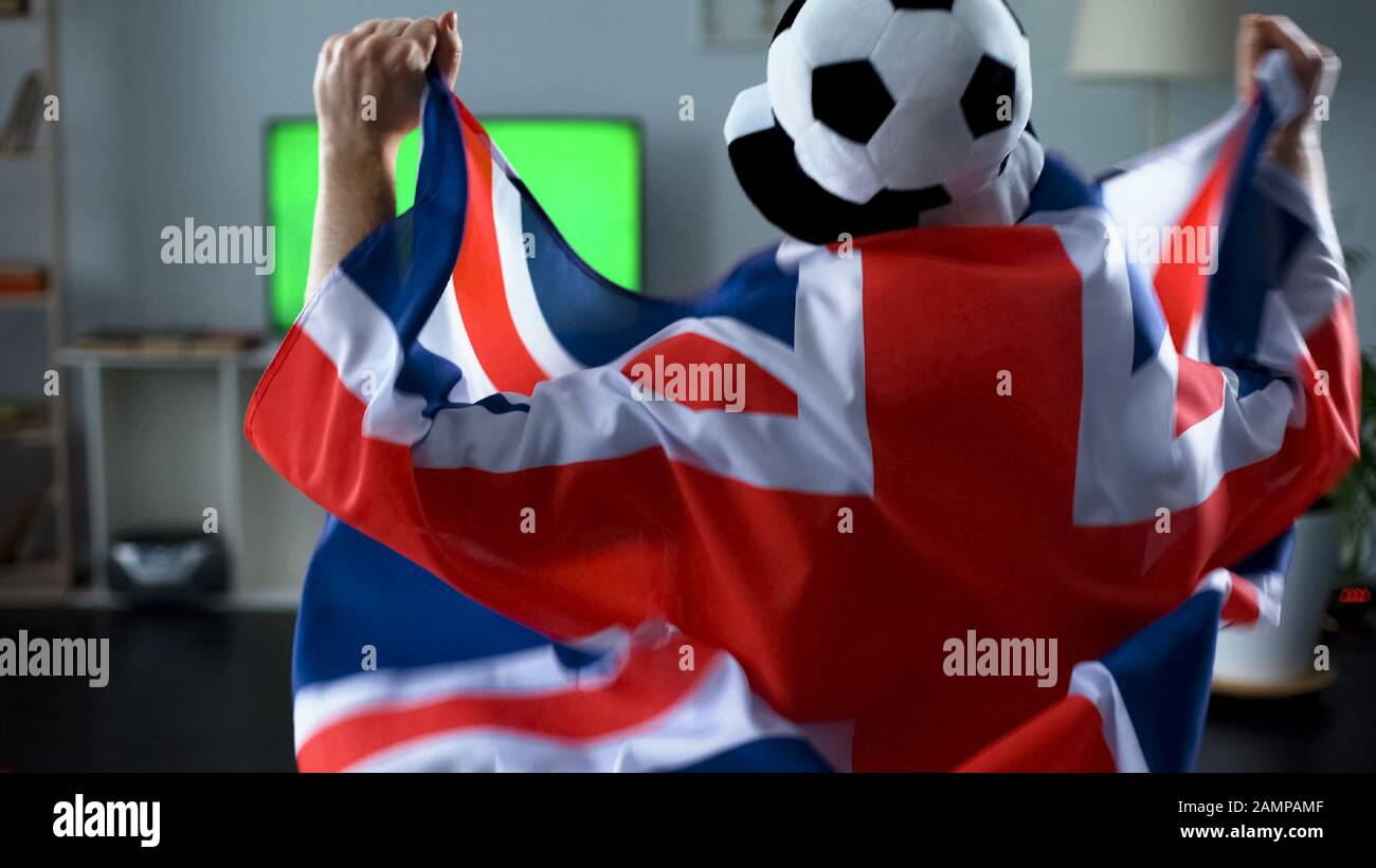 Mann, der die Flagge Großbritanniens hält, Anhänger beim Fußballspiel zu Hause im fernsehen Stockfoto