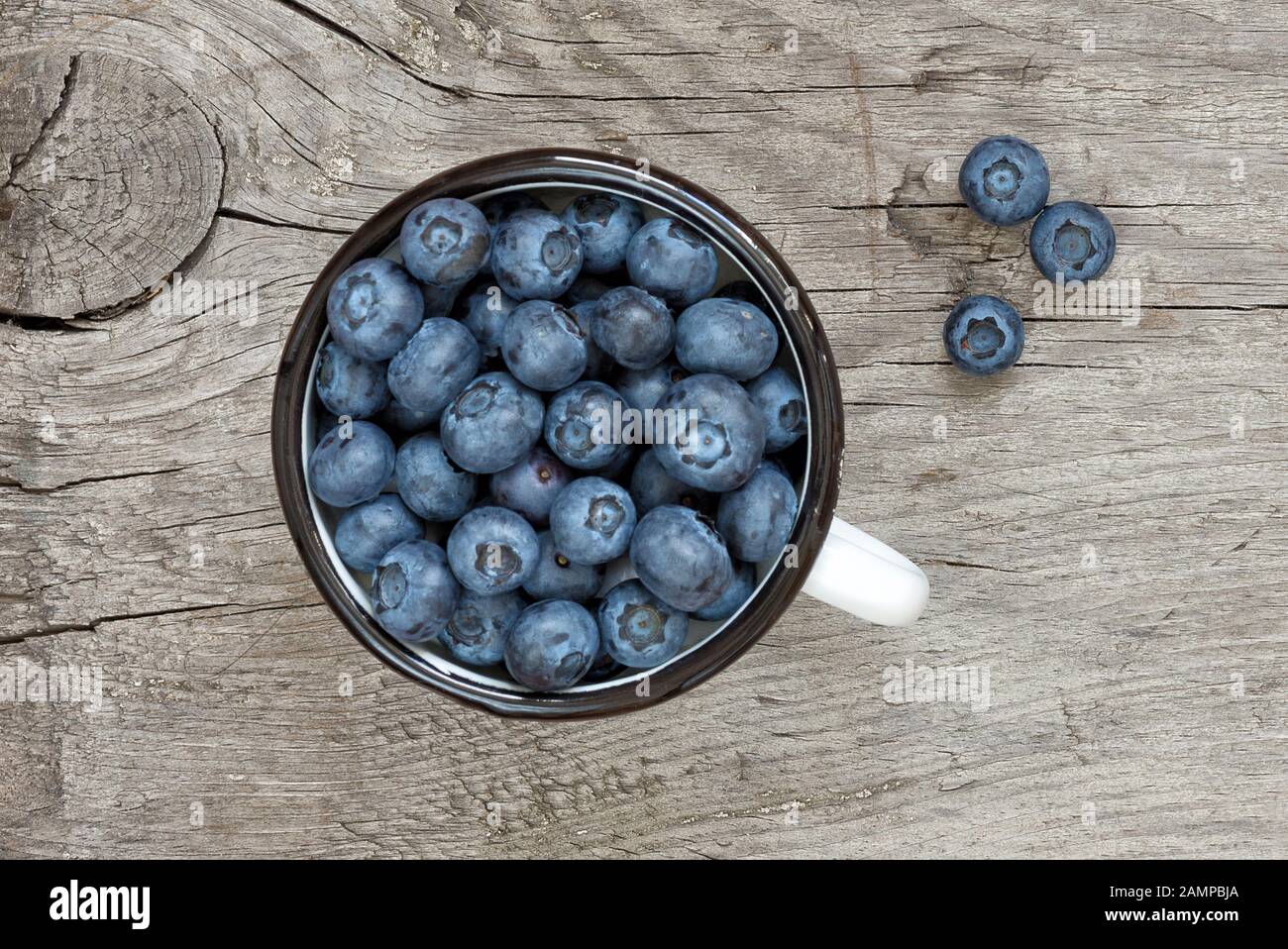Blaubeeren im alten Emailbecher auf Holzbrett mit Platz für Text; Draufsicht Stockfoto