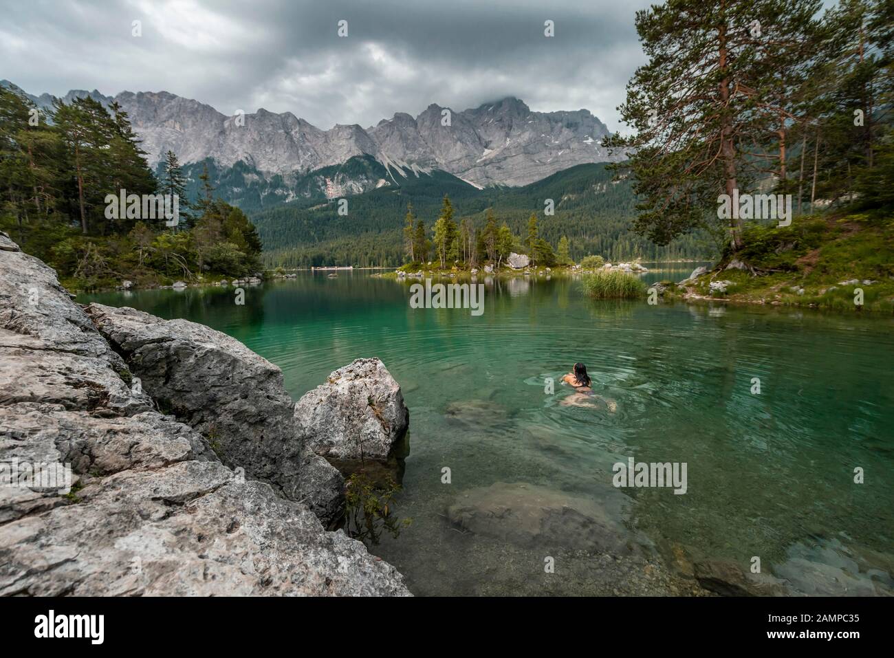 Frau schwimmt im See, Blick auf Eibsee vor Zugspitzmassiv mit Zugspitze, bewölkt, Wetterstein Range, bei Grainau, Oberbayern Stockfoto