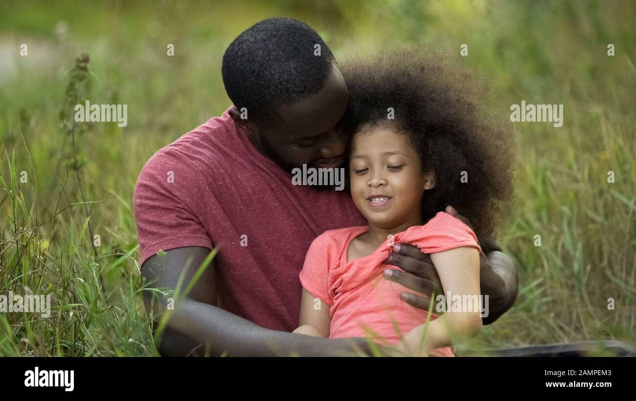 Liebevoller Vater umarmte seine winzige Tochter zärtlich und verbringt Zeit zusammen im Freien Stockfoto