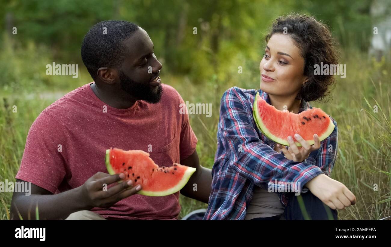 Flirrrriger gemischter Paare, der Pläne für die Zukunft diskutiert und köstliche Wassermelonen isst Stockfoto