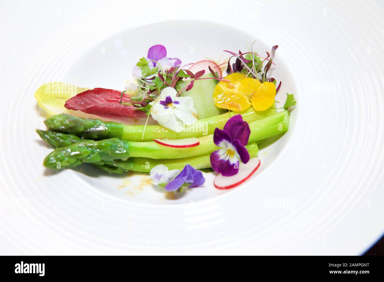Eine farbenprächtige Schale mit frischen Spargel mit Gurke, Salat und essbare Blumen serviert. Stockfoto